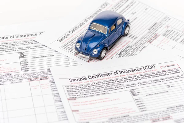 Carro de brinquedo azul em documentos de seguro em branco — Fotografia de Stock
