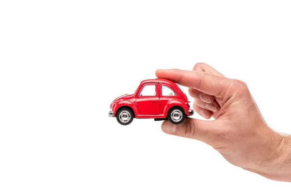 Vista recortada del hombre sosteniendo coche de juguete rojo en blanco - foto de stock