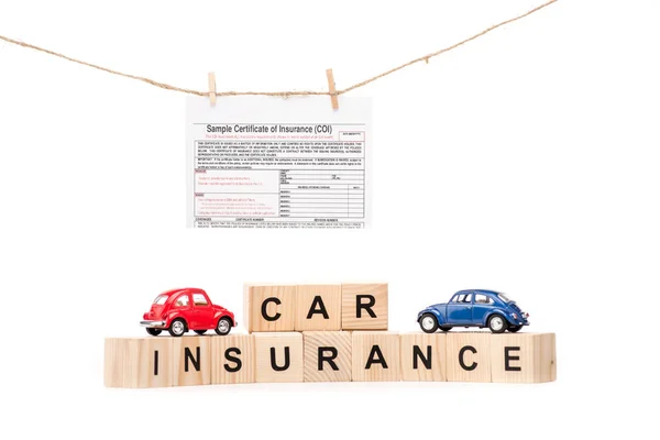 Toy cars, wooden blocks with letters and insurance document isolated on white — Stock Photo