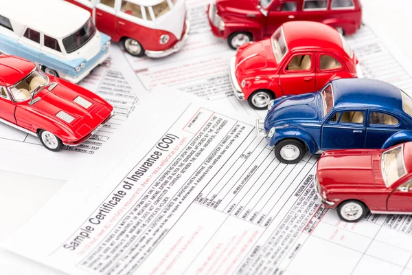 Coches de juguete rojos y azules en los documentos de seguro - foto de stock