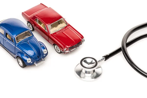 Красный и синий игрушечные автомобили и стетоскоп изолированы на белой поверхности — стоковое фото