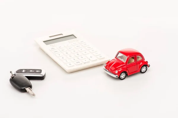 Chaves, carro de brinquedo vermelho e calculadora na superfície branca — Fotografia de Stock