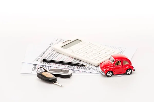 Ключи, калькулятор, страховые сертификаты и красный автомобиль игрушки на белой поверхности — стоковое фото