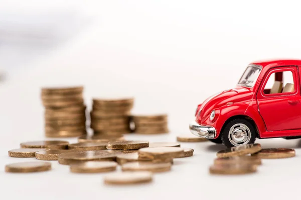 Красный игрушечный автомобиль и золотые монеты на белом — стоковое фото