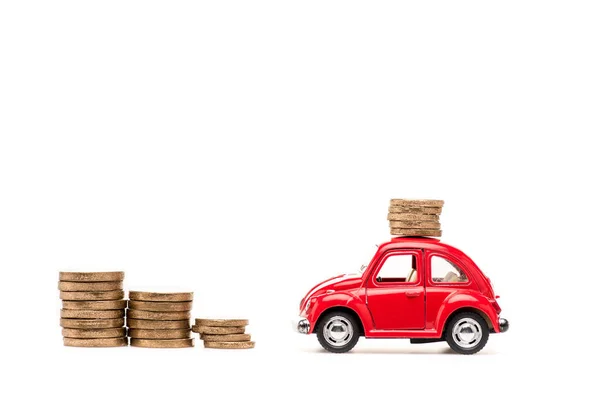 Coche de juguete rojo y monedas de oro en blanco - foto de stock