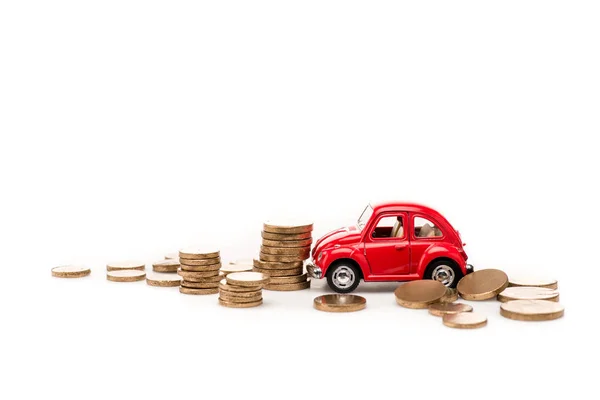 Coche de juguete rojo y monedas de oro en blanco - foto de stock