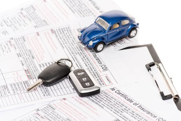 Coche de juguete azul, llaves, documentos de seguro y portapapeles aislados en blanco - foto de stock