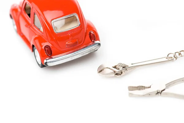 Foyer sélectif de voiture jouet rouge, clé et pinces sur la surface blanche — Photo de stock