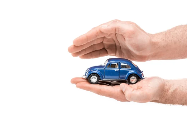 Обрізаний вид людини, що тримає синій іграшковий автомобіль ізольований на білому — стокове фото