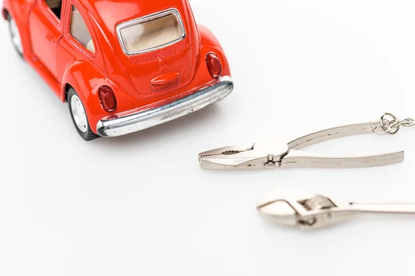 Селективный фокус гаечного ключа, плоскогубцев и красной игрушечной машины на белой поверхности — стоковое фото