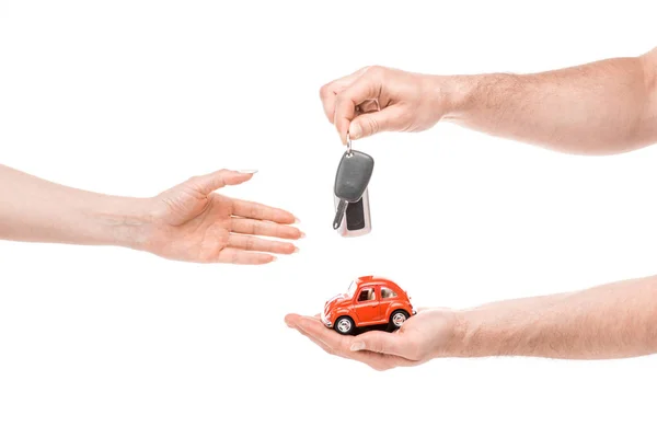 Visão cortada do homem dando carro de brinquedo e chaves para a mulher isolada no branco — Fotografia de Stock