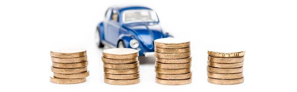 Tiro panorámico de monedas y coche de juguete azul en blanco - foto de stock