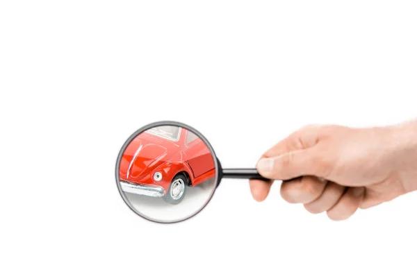 Cropped view of man holding magnifier in front of toy car isolated on white — Stock Photo