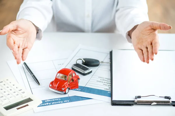 Ausgeschnittene Ansicht einer Frau in formeller Kleidung am Tisch mit Dokumenten, Spielzeugauto, Schlüsseln, Taschenrechner, Stift und Klemmbrett — Stockfoto