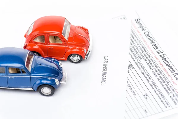 Red and blue toy cars on insurance certificates — Stock Photo