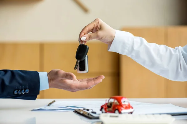 Cropped view of woman in formal wear giving man keys — Stock Photo