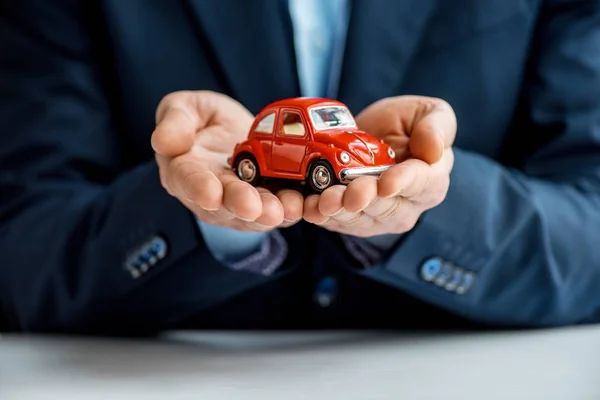 Partial view of man in formal wear holding red toy car — Stock Photo