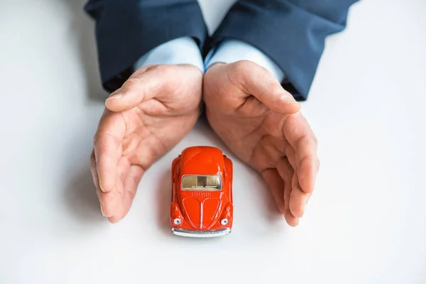 Vista cortada do homem em desgaste formal com carro de brinquedo vermelho — Fotografia de Stock