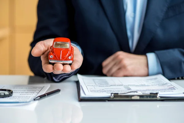 Vista parcial del hombre en desgaste formal sosteniendo coche de juguete rojo - foto de stock