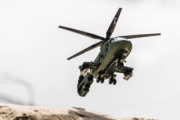 Jouet hélicoptère volant haut dans le ciel clair au-dessus du sable — Photo de stock