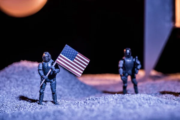 Selective focus of toy astronauts holding american flag in space — Stock Photo