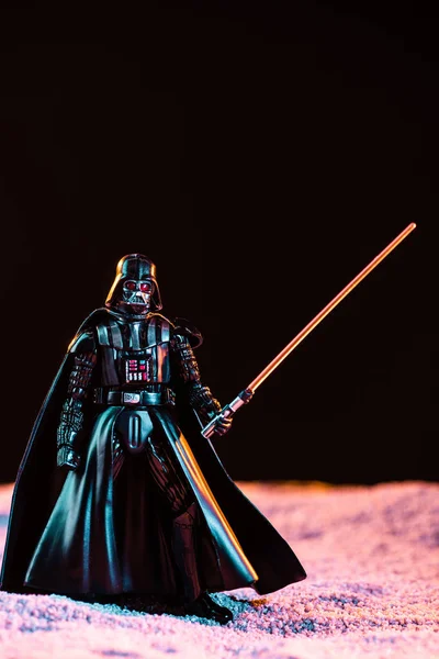 Darth Vader figurine with lightsaber isolated on black — стоковое фото