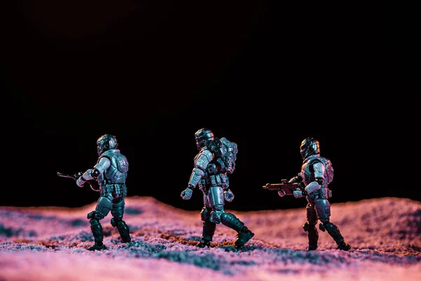 Jouets soldats marche avec arme sur planète dans l'espace isolé sur noir — Photo de stock