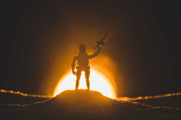 Silueta de soldado de juguete con pistola y sol en el fondo - foto de stock