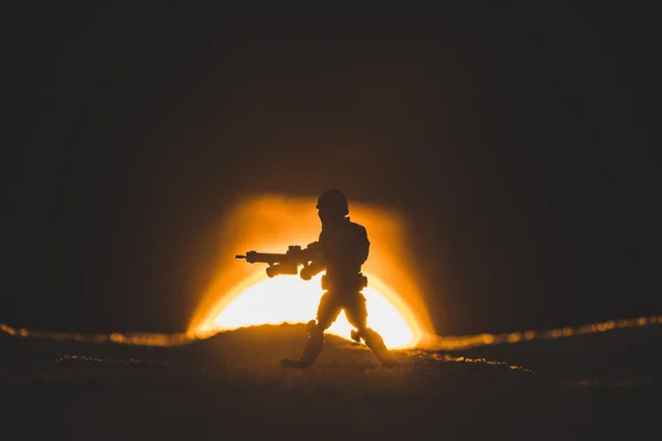 Silhouette de soldat jouet marchant avec un pistolet sur fond de soleil — Photo de stock