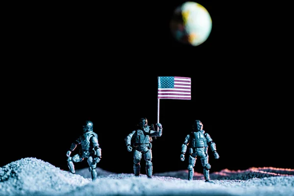 Soldados de brinquedo de pé com bandeira dos EUA no planeta no espaço em fundo preto com o planeta Terra — Fotografia de Stock