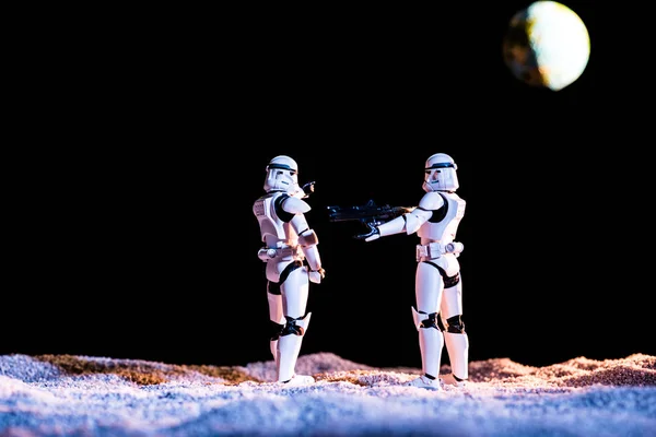 White imperial stormtroopers with gun on black background with planet Earth — Stock Photo