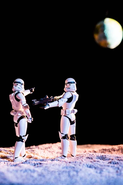 KYIV, UKRAINE - MAY 25, 2019: white imperial stormtrooper aiming with gun at another on black background with planet Earth — Stock Photo