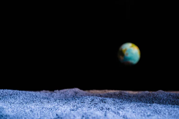 Textured ground with blurred planet Earth in space isolated on black — Stock Photo