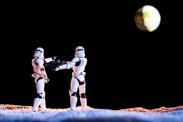 KYIV, UKRAINE - MAY 25, 2019: imperial stormtrooper aiming with weapon at another on black background with planet Earth — Stock Photo