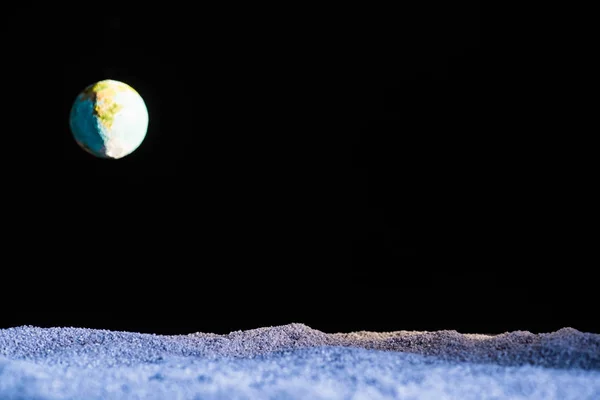 Піщана земля з розмитою планетою Земля в космосі ізольована на чорному — стокове фото
