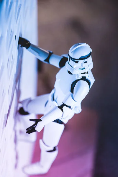Plastic Imperial Stormtrooper figurine climbing white textured wall — Photo de stock