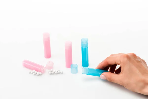 Cropped view of woman holding blue bottle near pills on white — Stock Photo