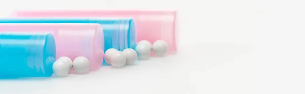 Panoramic shot of blue and pink bottles near pills on white — Stock Photo