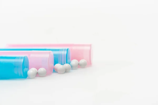 Bottiglie blu e rosa vicino pillole rotonde su bianco — Foto stock