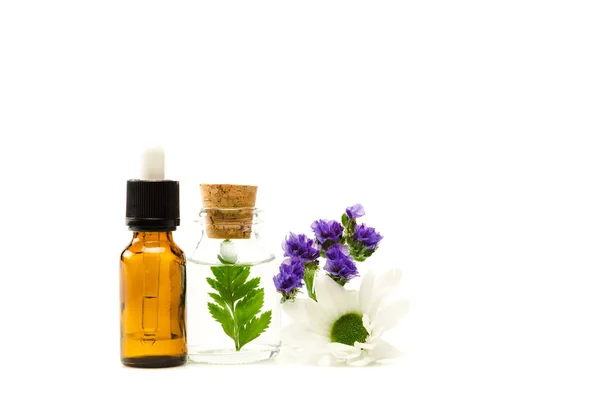 Bottles with liquid near limonium and chrysanthemum flowers isolated on white — Stock Photo