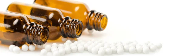 Панорамний знімок круглих таблеток біля пляшок на білому — стокове фото