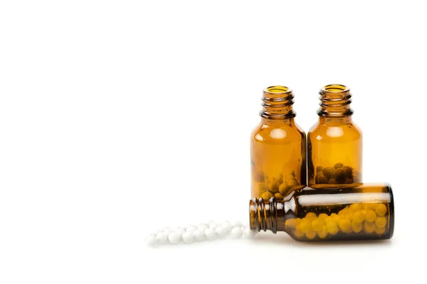 Pequenas pílulas redondas perto de garrafas de vidro isoladas em branco — Fotografia de Stock