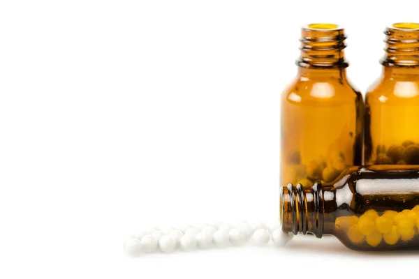 Pilules rondes près de bouteilles en verre isolées sur blanc avec espace de copie — Photo de stock