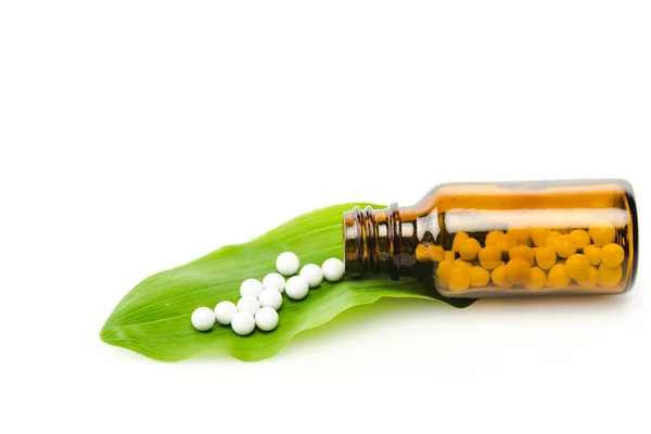 Frasco con la medicina cerca de hoja fresca verde aislado en blanco - foto de stock