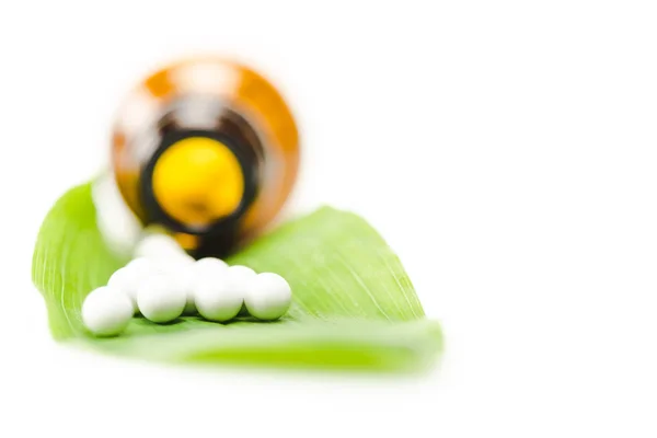 Селективний фокус невеликих круглих таблеток на зеленому листі біля пляшки ізольовані на білому — стокове фото