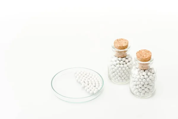 Bottles with wooden corks near glass petri dish isolated on white — Stock Photo