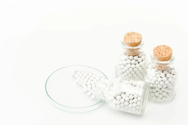 Bouteille avec de petites pilules rondes près de boîte de Pétri en verre isolé sur blanc — Photo de stock