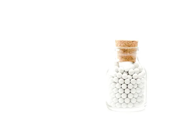 Comprimidos pequenos redondos em garrafa de vidro com cortiça de madeira isolada em branco — Fotografia de Stock