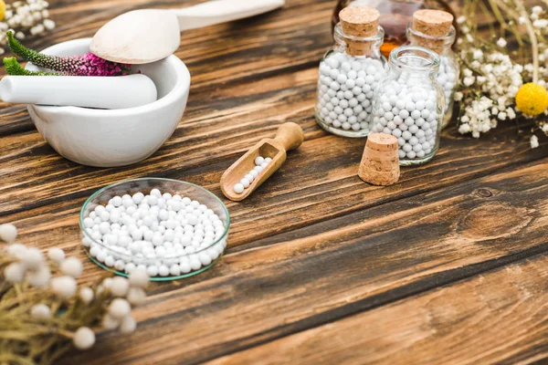 Foyer sélectif de bouteilles avec des pilules près de mortier avec des fleurs de veronica sur la table en bois — Photo de stock