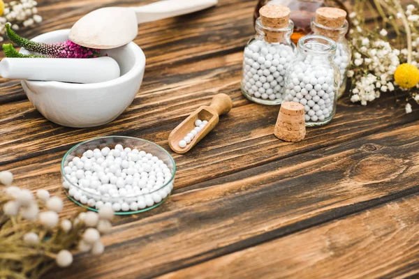 Selektiver Fokus von Flaschen mit Pillen in der Nähe von Mörser mit Veronika-Blumen auf Holztisch — Stockfoto